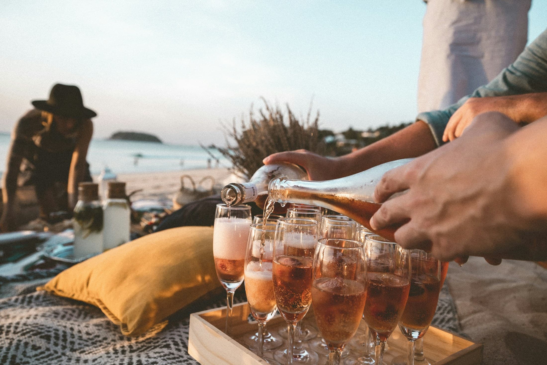 海辺の集まりでグラスに飲み物を注ぐ手元の写真